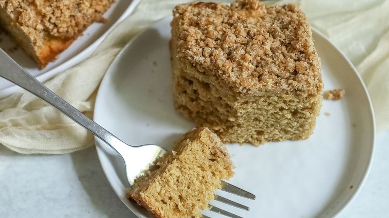 Slice of coffee cake on plate with bite removed by fork