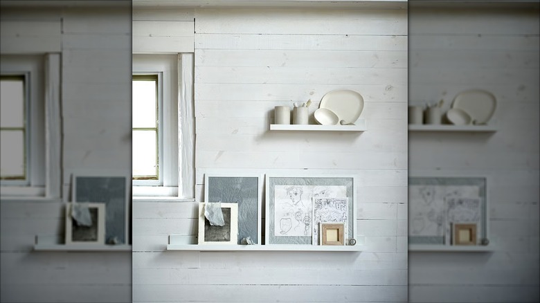 A white Ikea MOSSLANDA picture ledge holding plates and art on a wall.