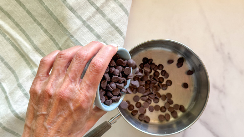hand adding chocolate chips to pot