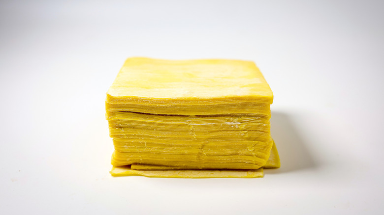 Stack of wonton wrappers on white background