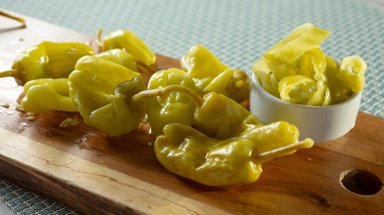 Pepperoncini peppers on a cutting board and sliced in a small bowl