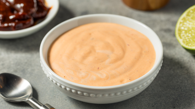 Closeup view of a bowl of chipotle mayo next to a bowl on chipotle in adobo on a table.