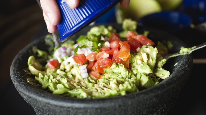 pouring ingredients on guacamole