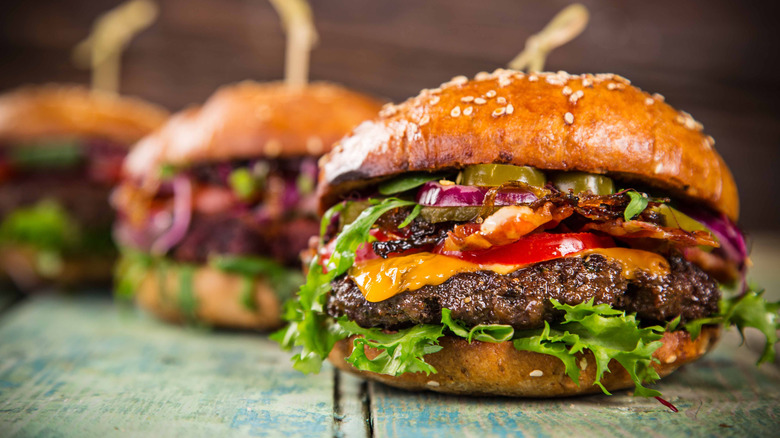 delicious looking hamburgers with lettuce cheese and a sesame seed bun