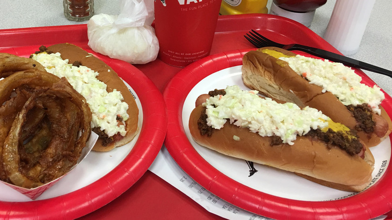 Atlanta-style hot dogs with chili and coleslaw on paper plates on a red plastic tray