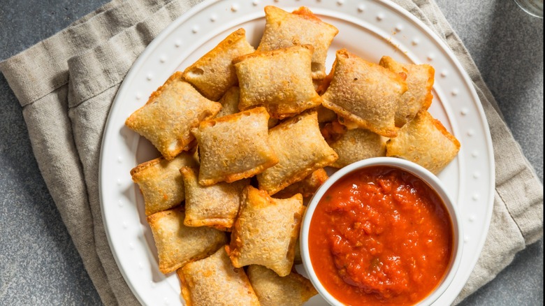 A plate of pizza rolls with marinara sauce on the side