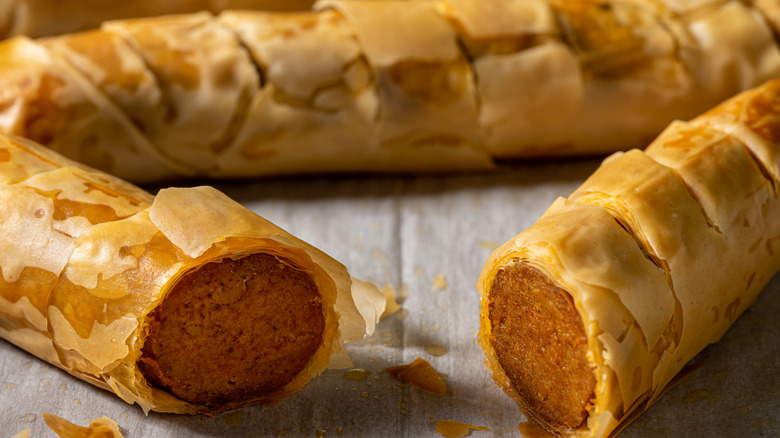 Hot dogs wrapped in thin, crispy looking phyllo dough cut in half to show the inside