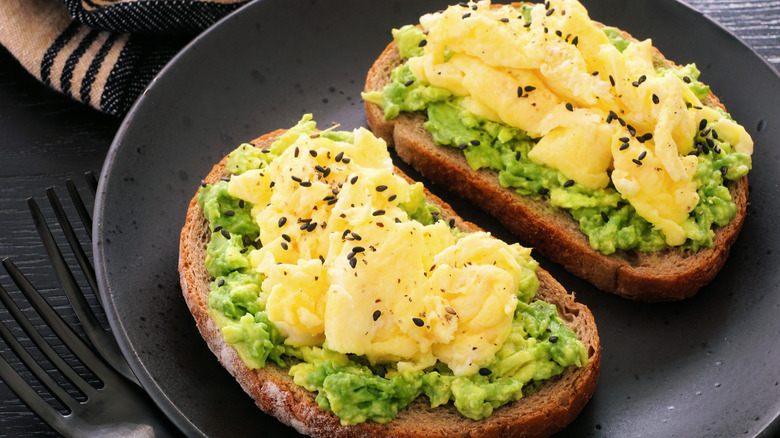 A plate of sourdough bread with scrambled eggs and avocado