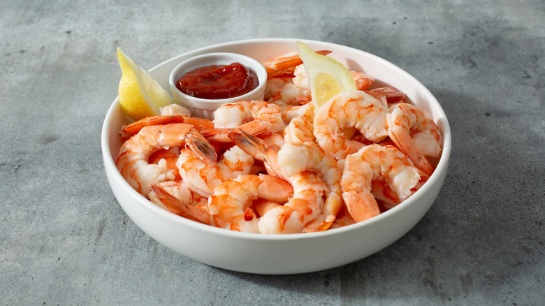 Shrimp cocktail plate with sauce and lemon wedges