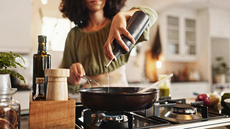 woman adding oil to pan