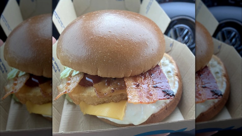 Filet-O-Fish sandwich with several additions, including bacon, lettuce, and a dark sauce