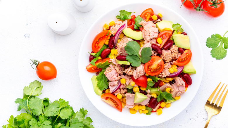 a plate of canned tuna with Mexican-inspired ingredients like tomatoes, onion, corn, beans, and cilantro