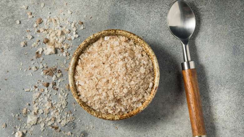 A small bowl of smoked sea salt next to a spoon