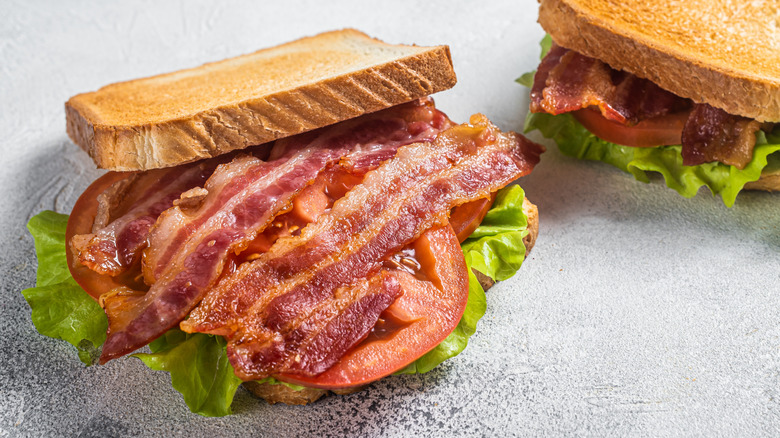 BLT sandwich with the top slice of bread pulled back to show the bacon, lettuce, and tomatoes