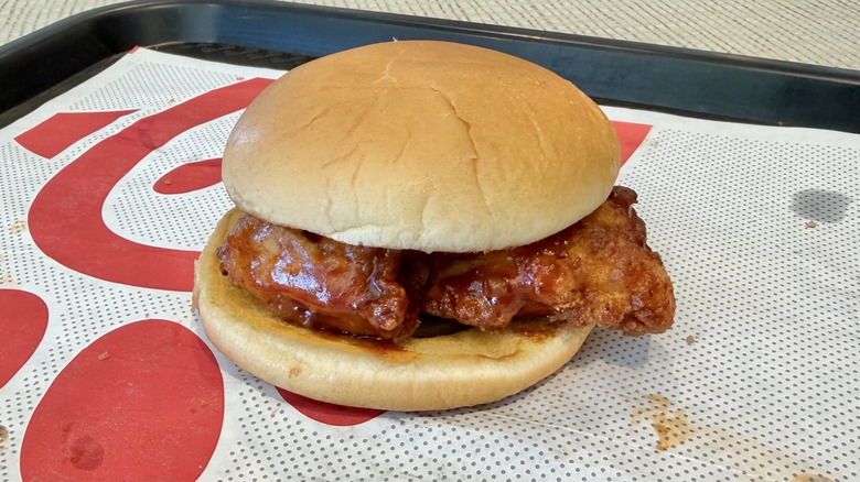 A Chick-Fil-A chicken sandwich, dressed in honey and barbecue sauce