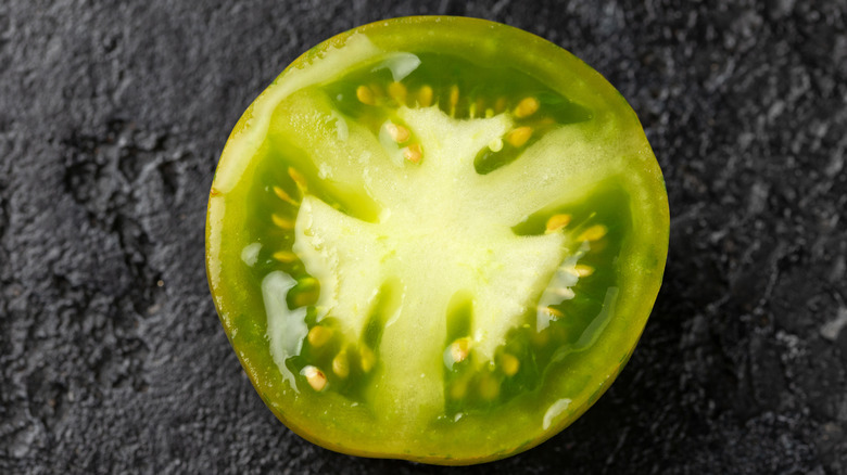 A green tomato slice against black background