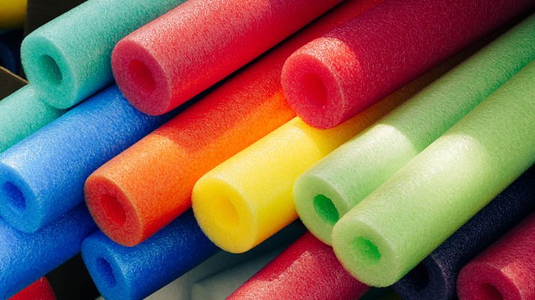 A colorful bunch of pool noodles stacked together