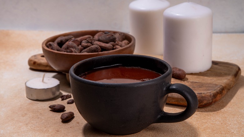 Mug of hot cocoa with candles, cacao beans
