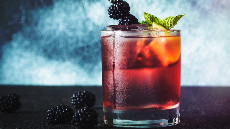 A whiskey and blackberry cocktail garnished with fresh blackberries and mint