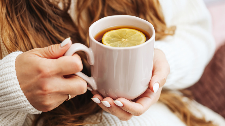 Hands holding a Long Island Tea served toddy-style in a mug