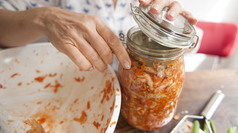 Person closing jar of kimchi next to prep bowl