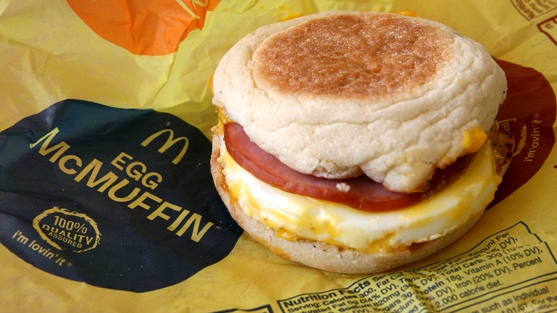 McDonald's Egg McMuffin sandwich with egg, cheese, and Canadian bacon sitting on yellow paper wrapper