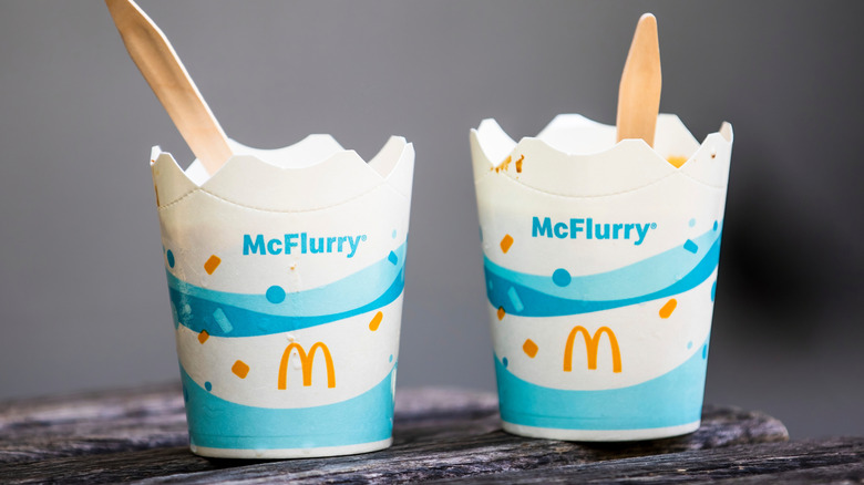 Two McDonald's McFlurry dessert cups with light blue patterned design and wooden spoons on dark surface