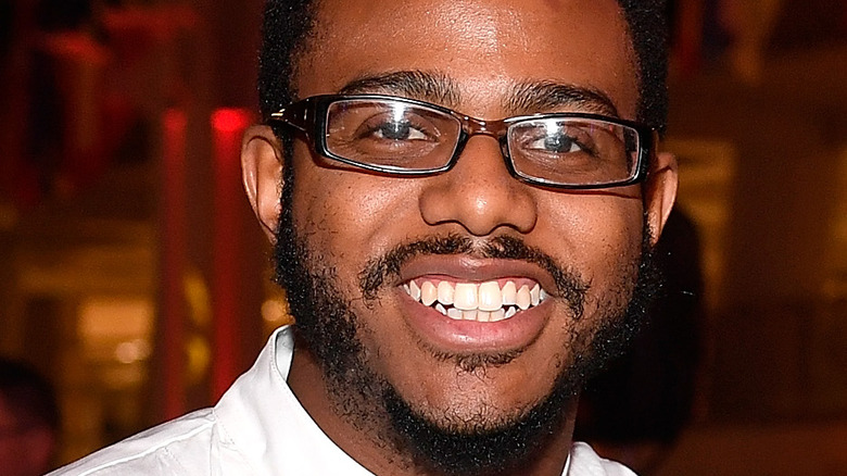 Kwame Onwuachi smiling in square glasses