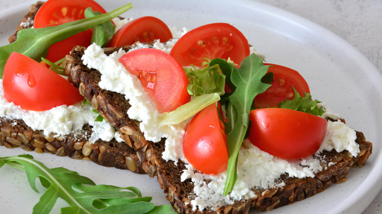 cottage cheese and tomatos on rye bread with fresh herbs