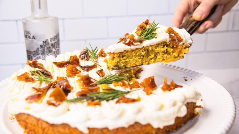 Serving a slice of gluten-free lemon olive oil cake from a cake stand.