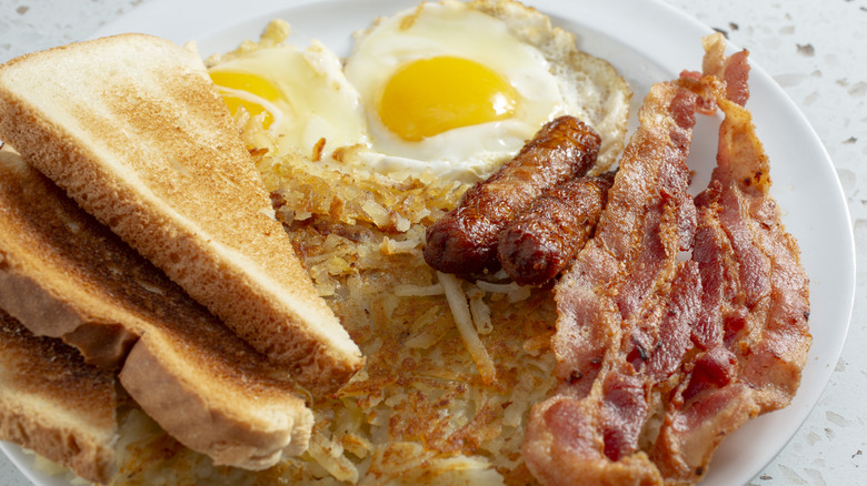 Breakfast platter with eggs, toast, sausage, bacon, and hash browns