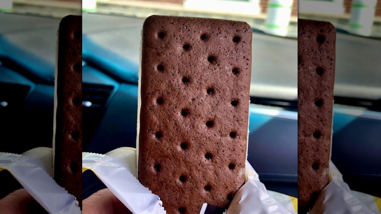 Hand holding unwrapped Good Humor Giant Vanilla Sandwich.