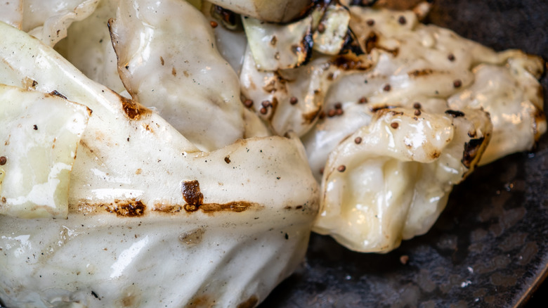 Large pieces of charred grilled cabbage rest on a plate.
