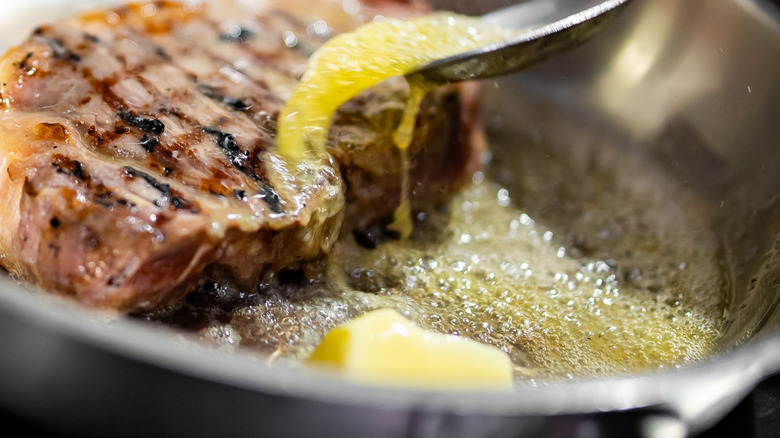 spoon benerously butter basting light meat in a pan