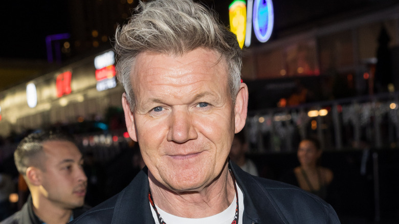 Gordon Ramsay smiles in a white t-shirt and dark collared jacket