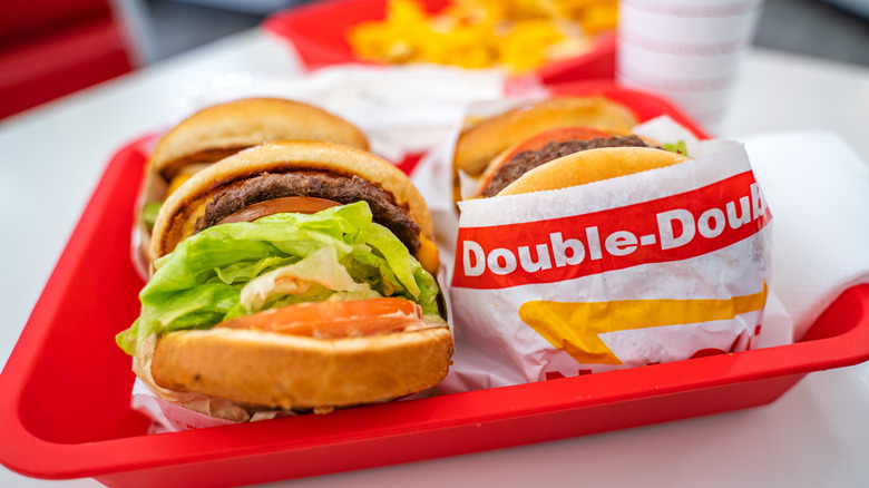 Several In-N-Out burgers wrapped in paper on a red tray