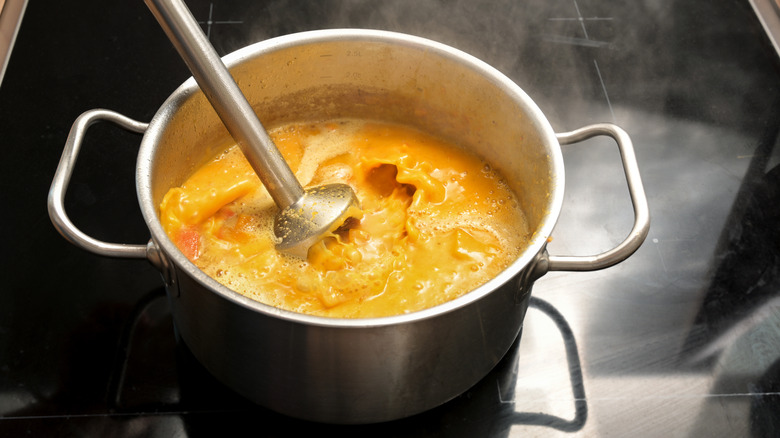 pureeing a pot of squash soup with an immersion blender