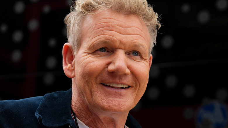 Gordon Ramsay smiling in a white shirt and navy blue jacket