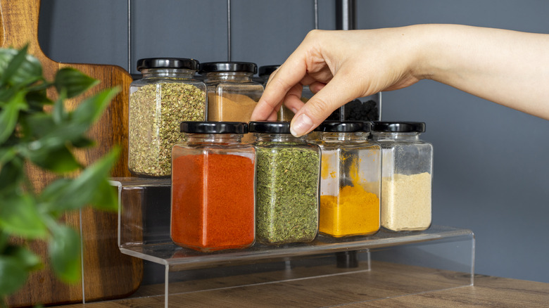 hand reaching for jar from racks of spices and herbs