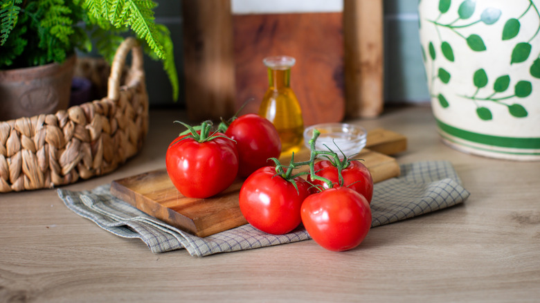Ripe red vine tomatoes and olive oil on a wooden kitchen countertop
