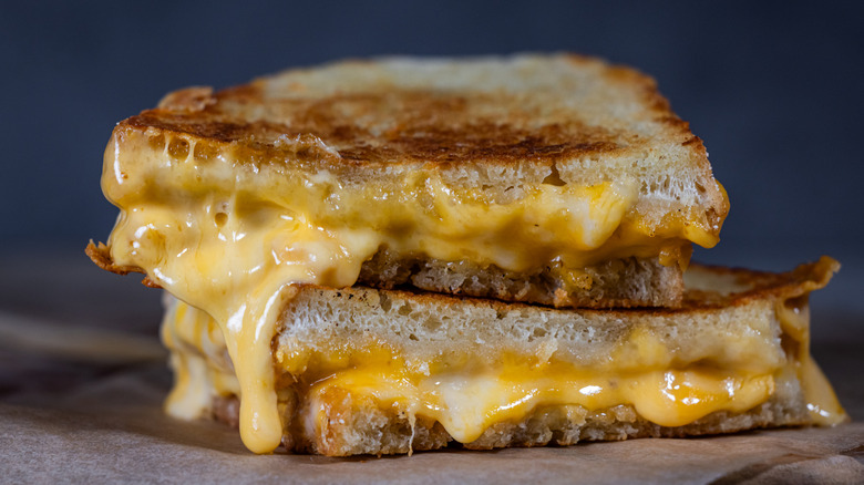 Two halves of a grilled cheese sandwich stacked on each other oozing melted cheese
