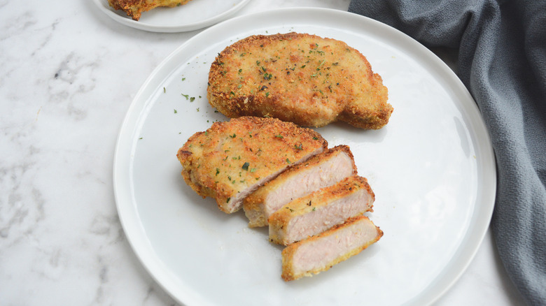Parmesean-crusted pork chop sliced on a plate.