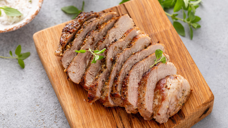 A grilled pork chop sliced on a cutting board.