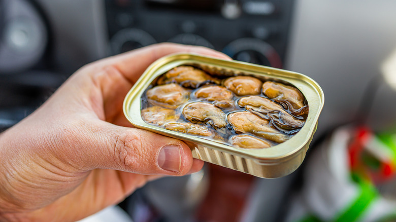 person holding can of oysters