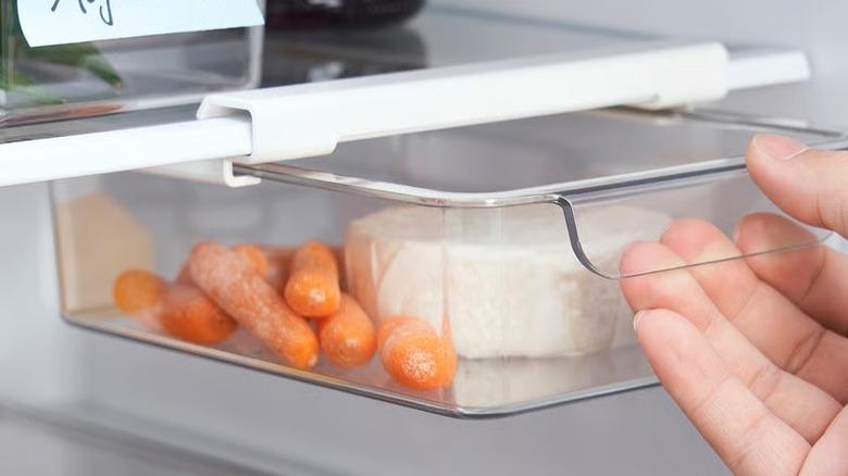 Klippkaktus storage box with cheese and carrots in it being opened by hand
