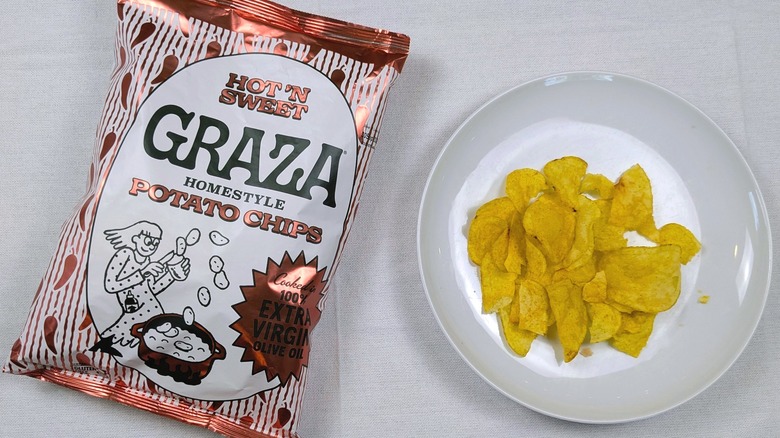 A bag of Graza Hot N' Sweet potato chips and a white plate of chips on a white tablecloth