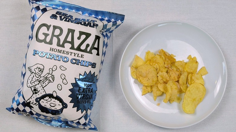 A bag of Graza Sea Salt & Vinegar potato chips and a white plate of chips on a white tablecloth
