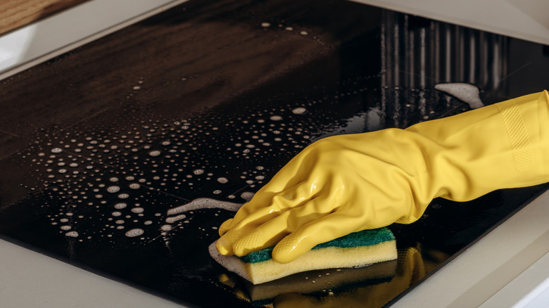 Someone cleaning a glass stove top
