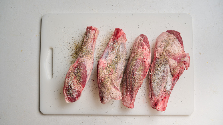 seasoning lamb shanks on a cutting board
