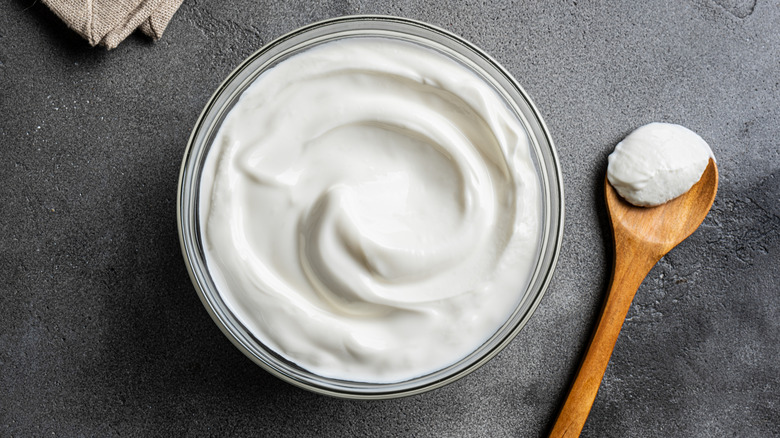 Greek yogurt in bowl with wooden spoon